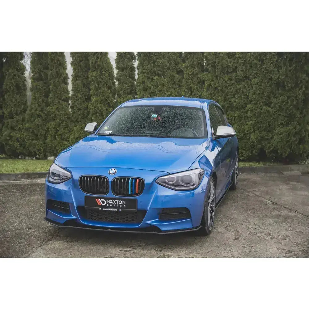 Frontspoiler på blå BMW M135i F20 med sorte detaljer og regnvann på panseret, sett forfra.