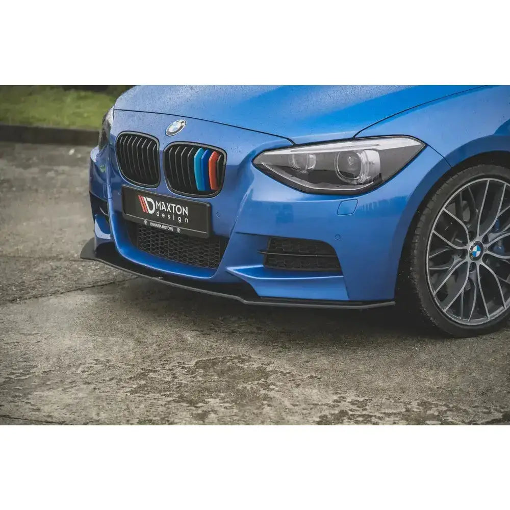 Front lip på BMW M135i F20 med svart spoiler og fargerike grillriller, sett fra lav vinkel foran.