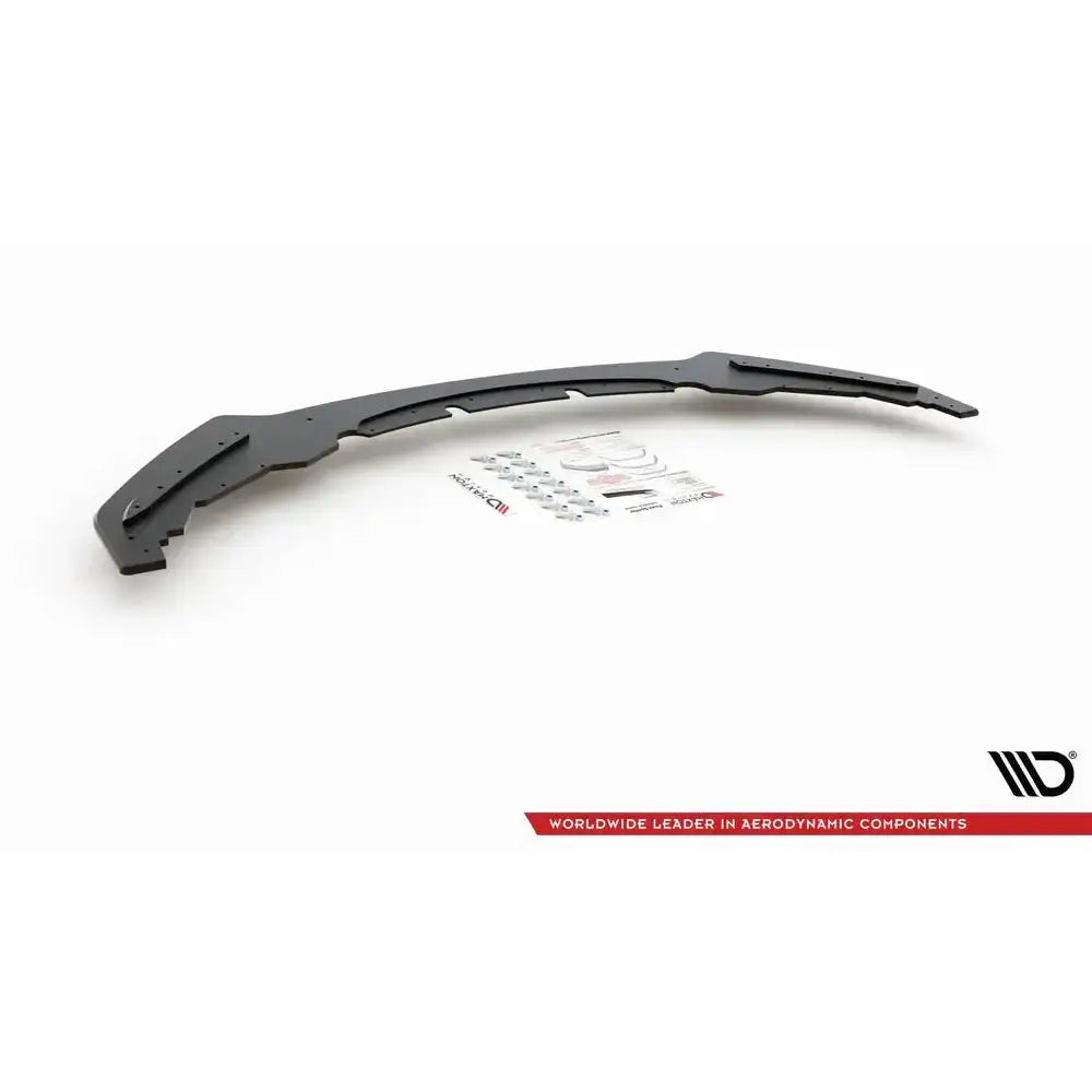 Frontspoiler til BMW M135i F20, sort buet del med monteringsdeler og klistremerker på hvit bakgrunn.