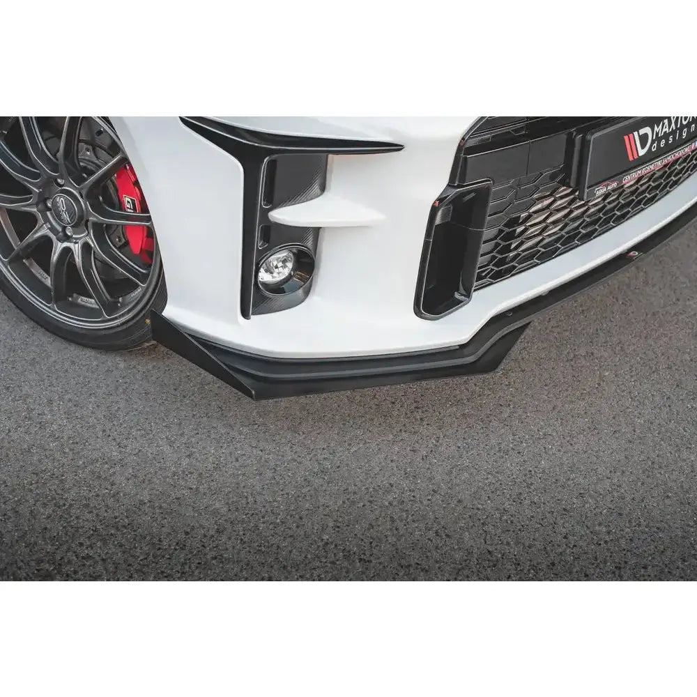 Frontsplitter på hvit Toyota GR Yaris MK4 med sporty felger og røde bremsekalipere på asfalt.