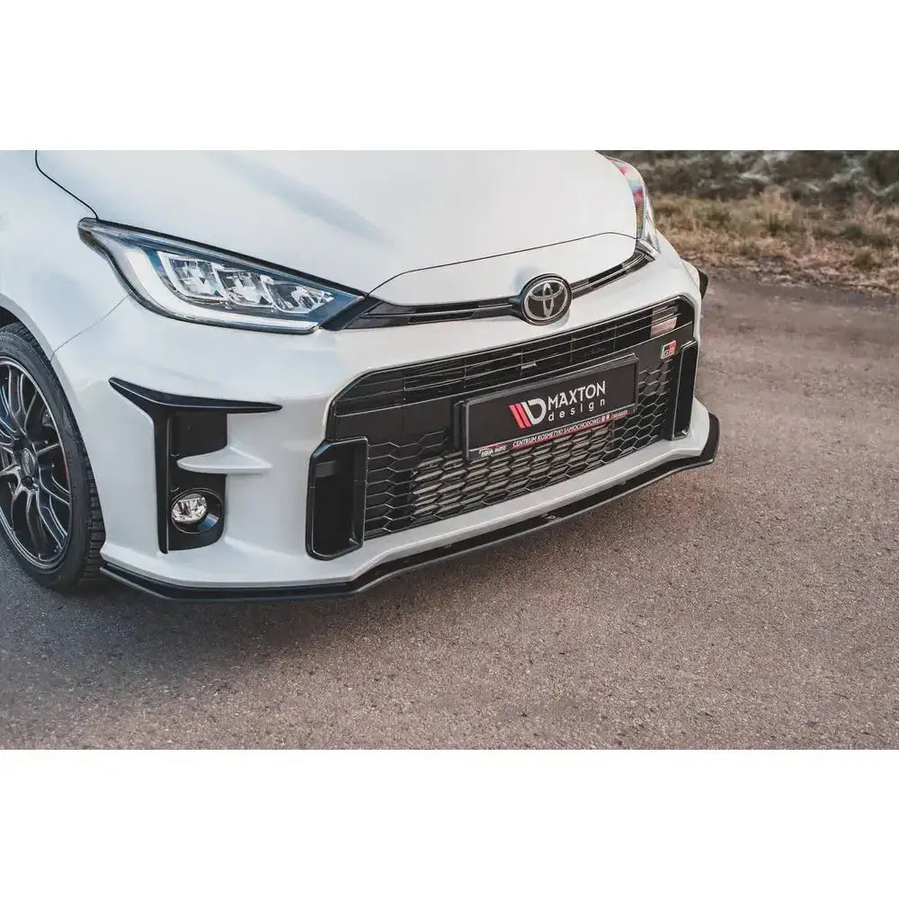 Frontsplitter Racing Durability montert på hvit Toyota GR Yaris MK4 med svart grill og sportsfelger.