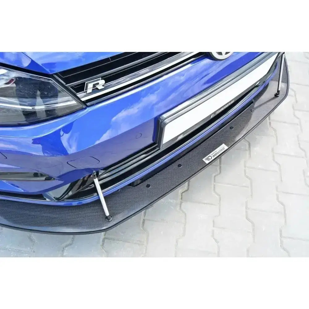 Frontspoiler Racing Hybrid Vw Golf VII R med sort karbonfiber og metallstøtter under blå bil.