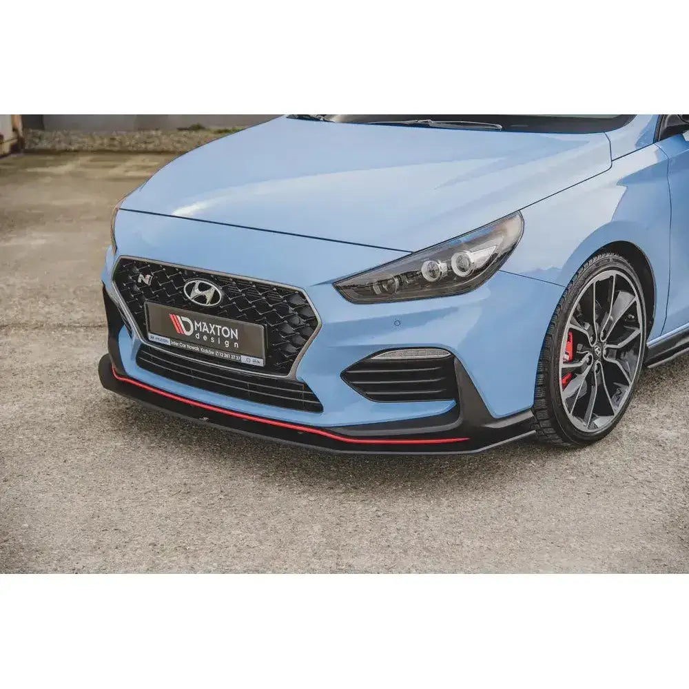 Front lip på Hyundai I30 N Mk3 med sort frontleppe, rød stripe og sportsfelger sett skrått forfra.