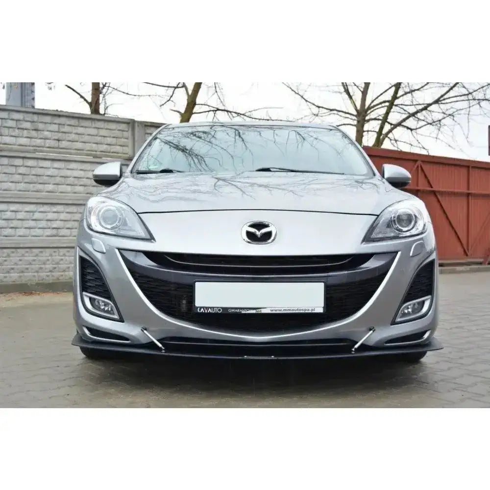 Frontsplitter på Mazda 3 Mk2 Sport, sølvfarget bil med svart spoiler, tåkelys og parkert foran murvegg.