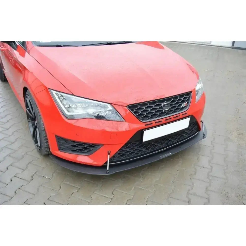 Frontsplitter til Seat Leon III Cupra, sort plast med metallstag, montert på rød bil foran asfalt.