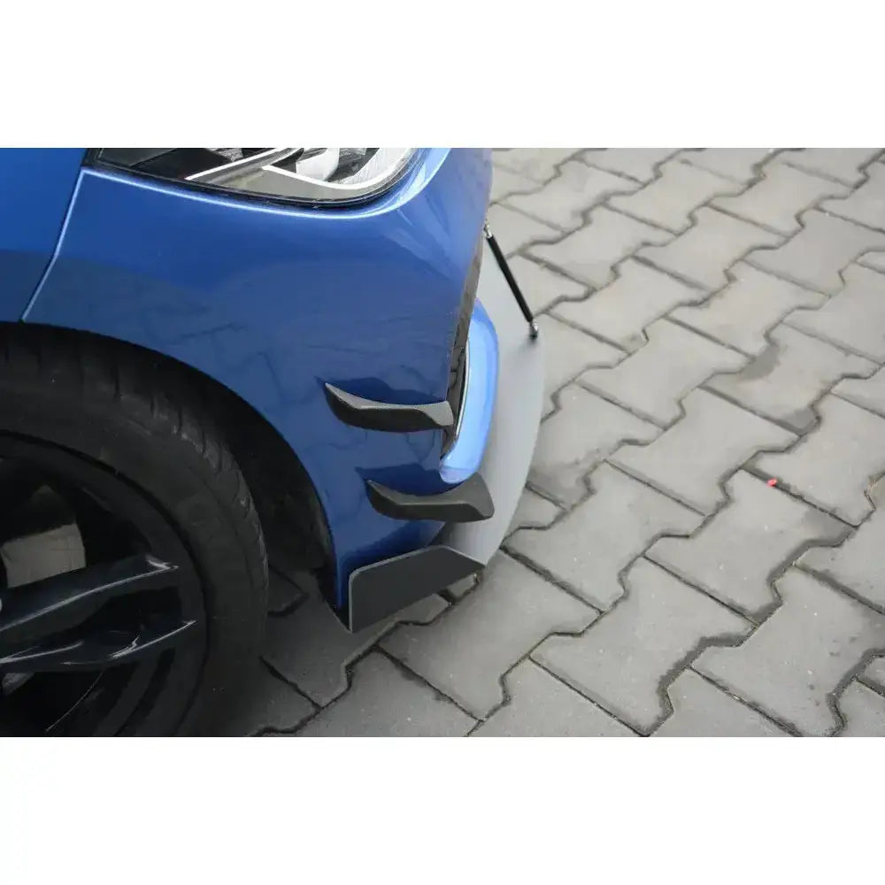 Front splitter på blå BMW 1 F20/F21 M-Power Facelift med svarte finner og spoilerleppe mot brostein.