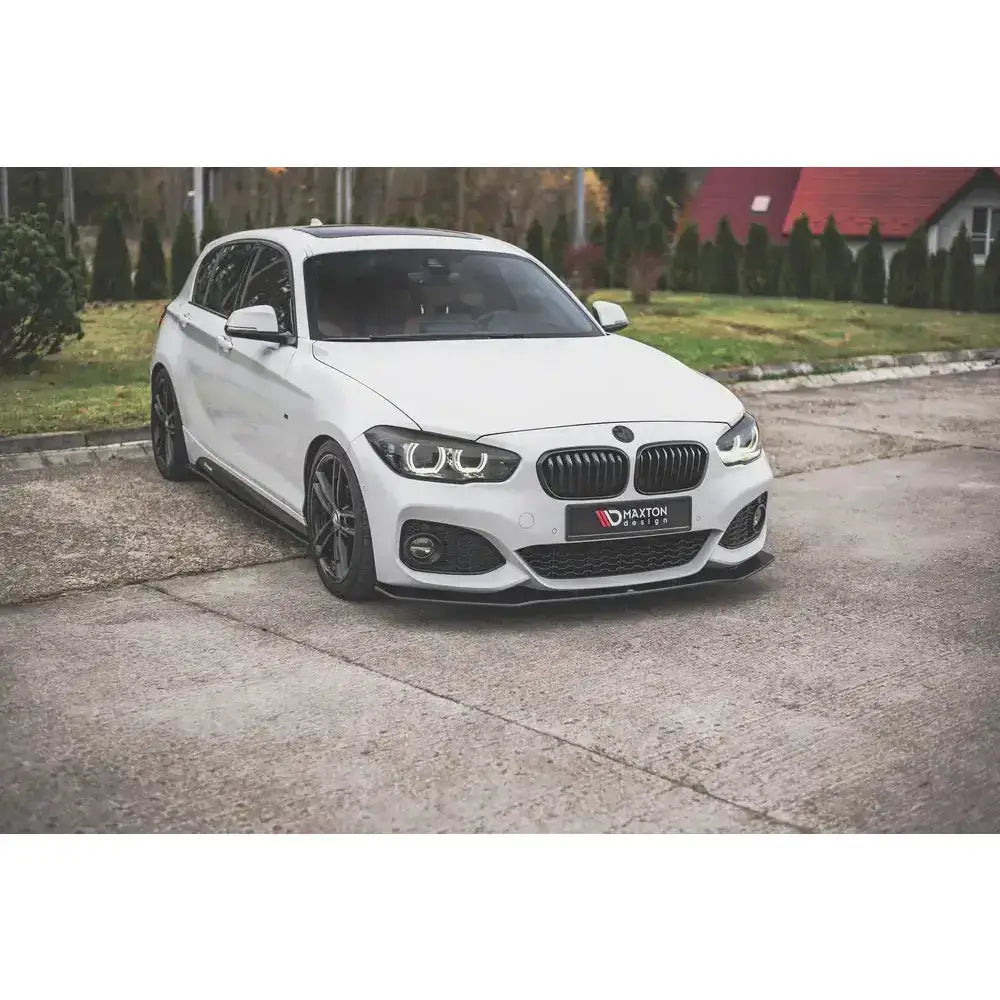 Frontspoiler på hvit BMW 1 F20 M-Pack Facelift med sorte detaljer og sportslige felger, parkert ute.