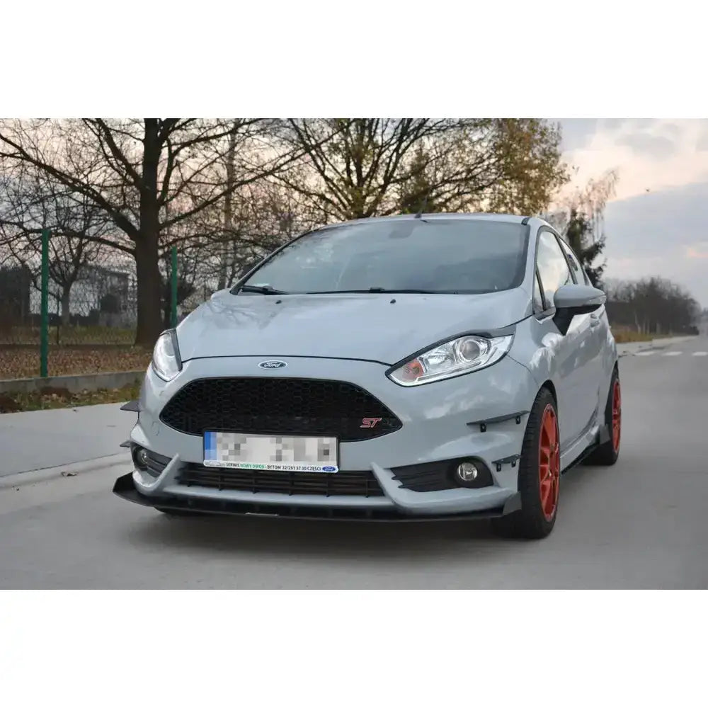 Frontspoiler Racing V.3 på lysegrå Ford Fiesta Mk7 ST med røde felger og synlig ST-emblem.