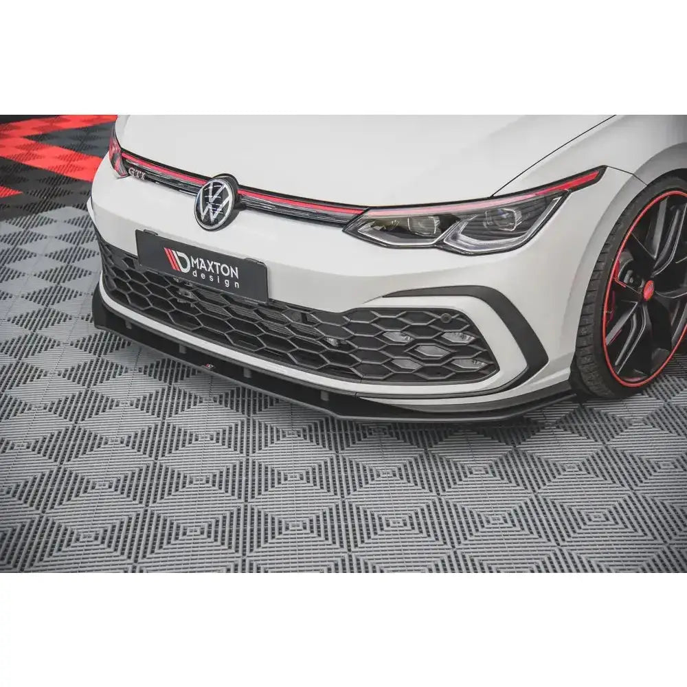 Frontsplitter på Volkswagen Golf 8 GTI med svart og rød dekor, detaljerte felger med rød kant.