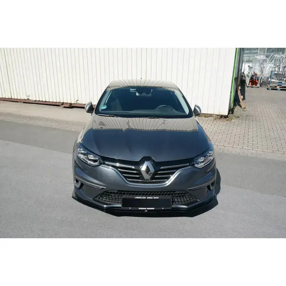 Front lip på Renault Megane Mk.4 Gt-Line, mørk grå bil med blanke detaljer parkert foran industrivegg.
