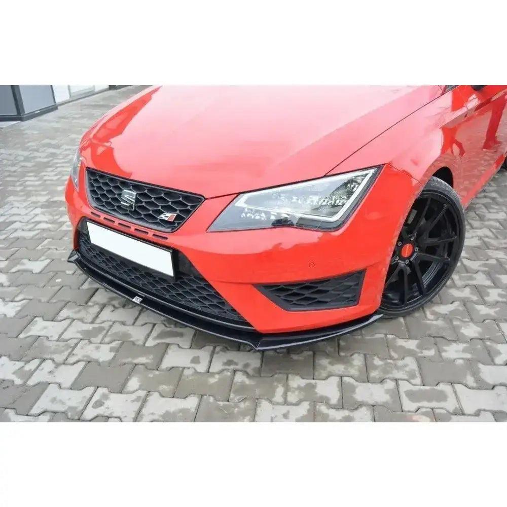 Frontspoiler på rød Seat Leon III Cupra med sort grill, sorte felger og spoiler, sett fra lav vinkel.