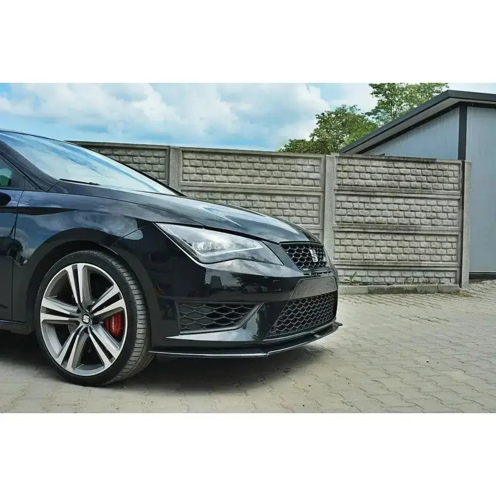 Front lip Seat Leon III Cupra med sorte aluminiumsfelger og rød bremsekaliper foran murvegg.