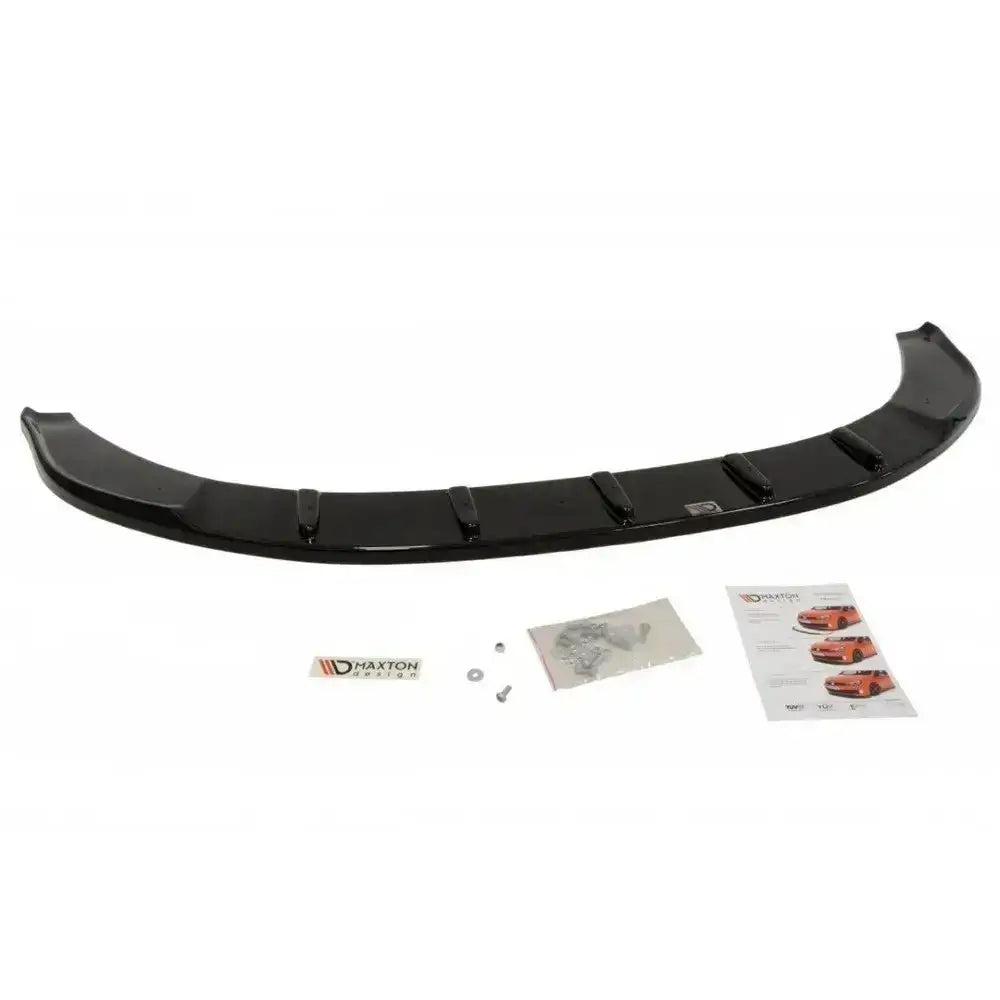 Frontspoiler til Skoda Superb II i sort, blank plast sett ovenfra med tilbehør som skruer og instruksjonshefte.