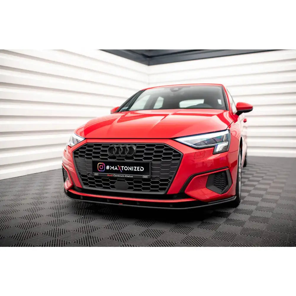 Frontspoiler på Audi A3 8Y Street Pro, rød bil med svart grill og LED-lykter i lyst rom.
