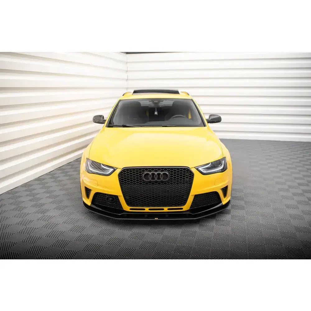 Front lip Street Pro Audi RS4 B8 montert på gul bil sett forfra med sort grill, innendørs.