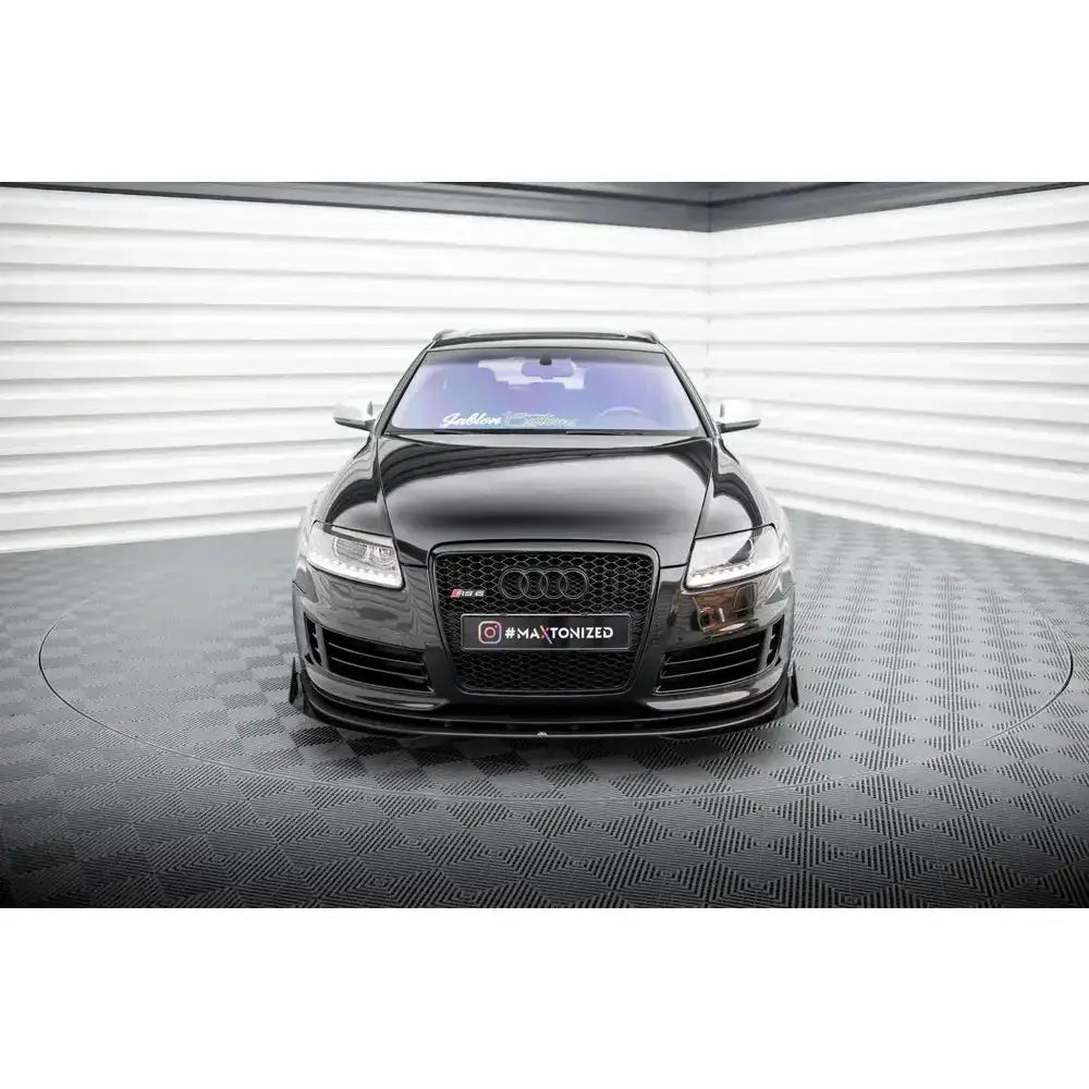 Frontspoiler Street Pro med flaps på Audi RS6 C6, sett forfra på rutete gulv og lys bakgrunn.