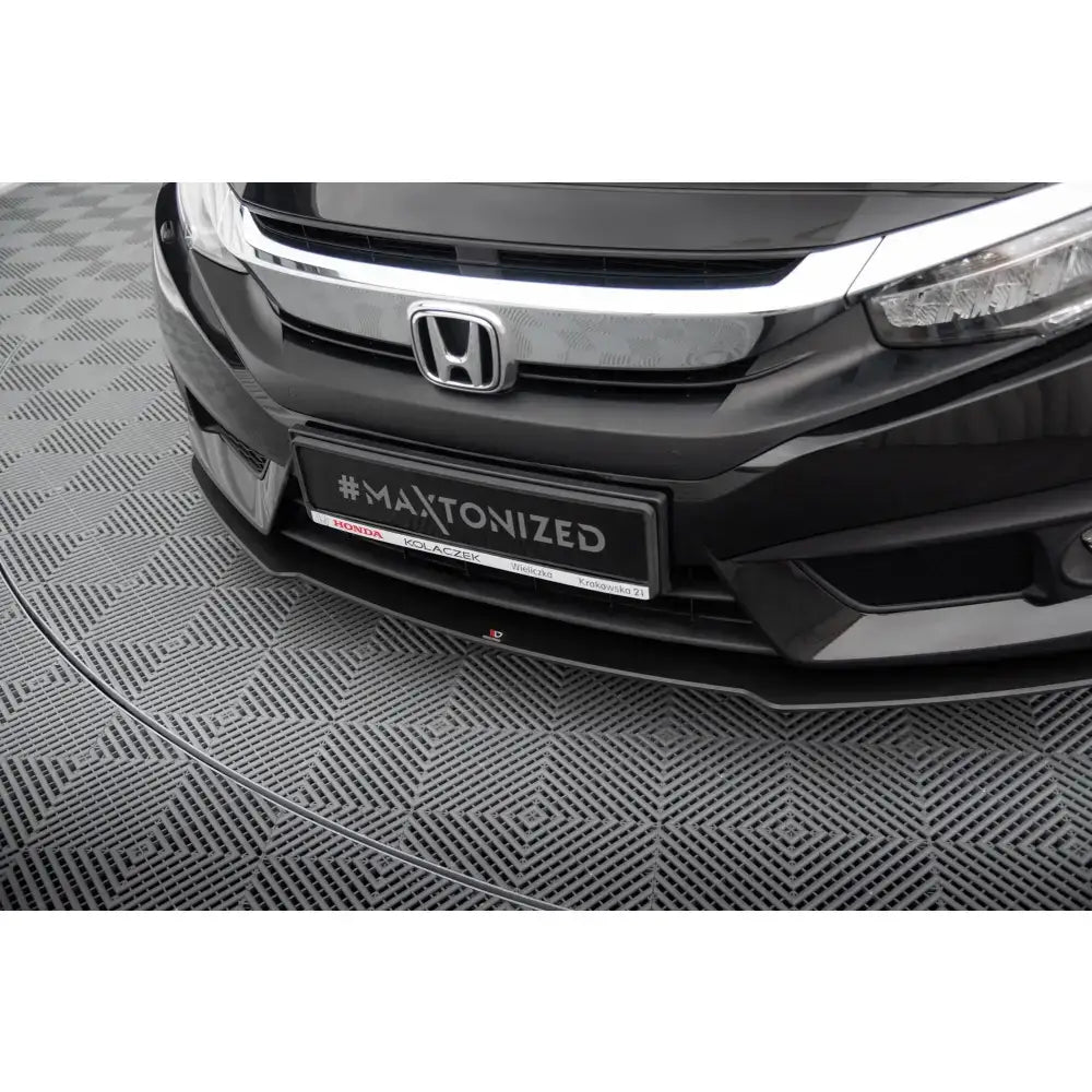 Front lip Street Pro Honda Civic Mk10 i sort plast montert under støtfanger på grått mønstret gulv.