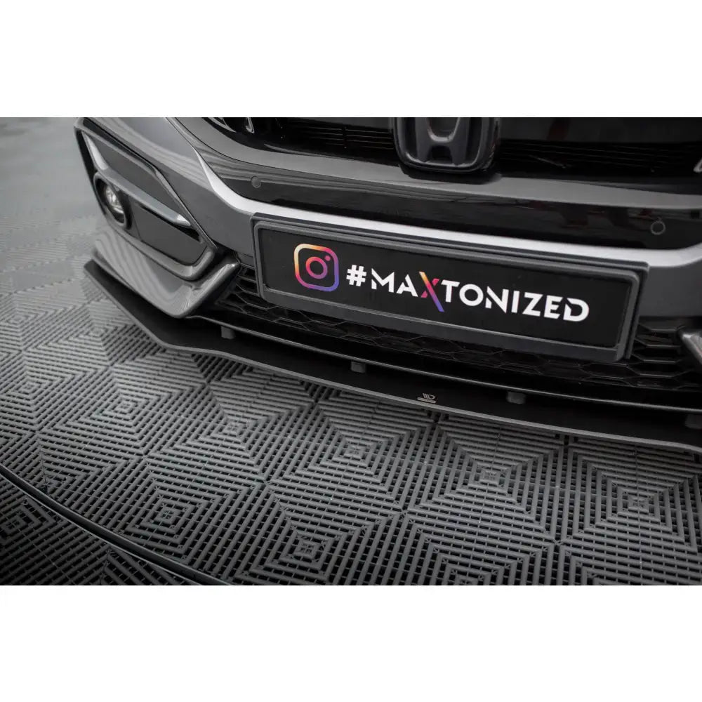 Front lip Street Pro Honda Civic Sport Mk 10 sett nedenfra med glanset sort overflate mot mønstret gulv.