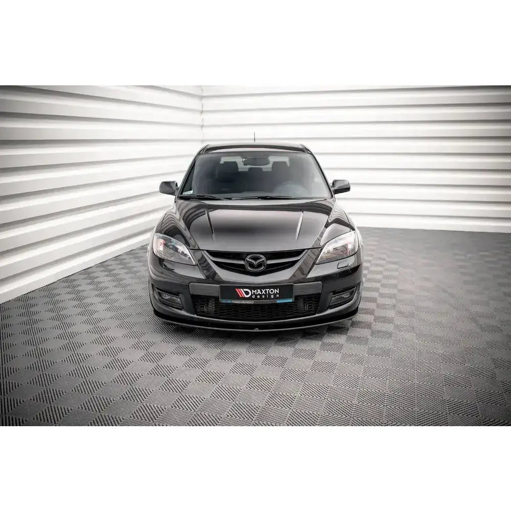 Frontspoiler på Mazda 3 MPS Mk1 06-08 i svart, sett rett forfra i lyst rom med rutet gulv.