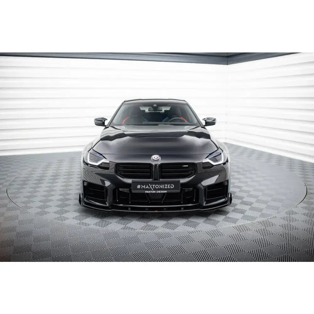Frontsplitter Street Pro V1 med flaps montert på sort BMW M2 G87 sett rett forfra i lyst studio.