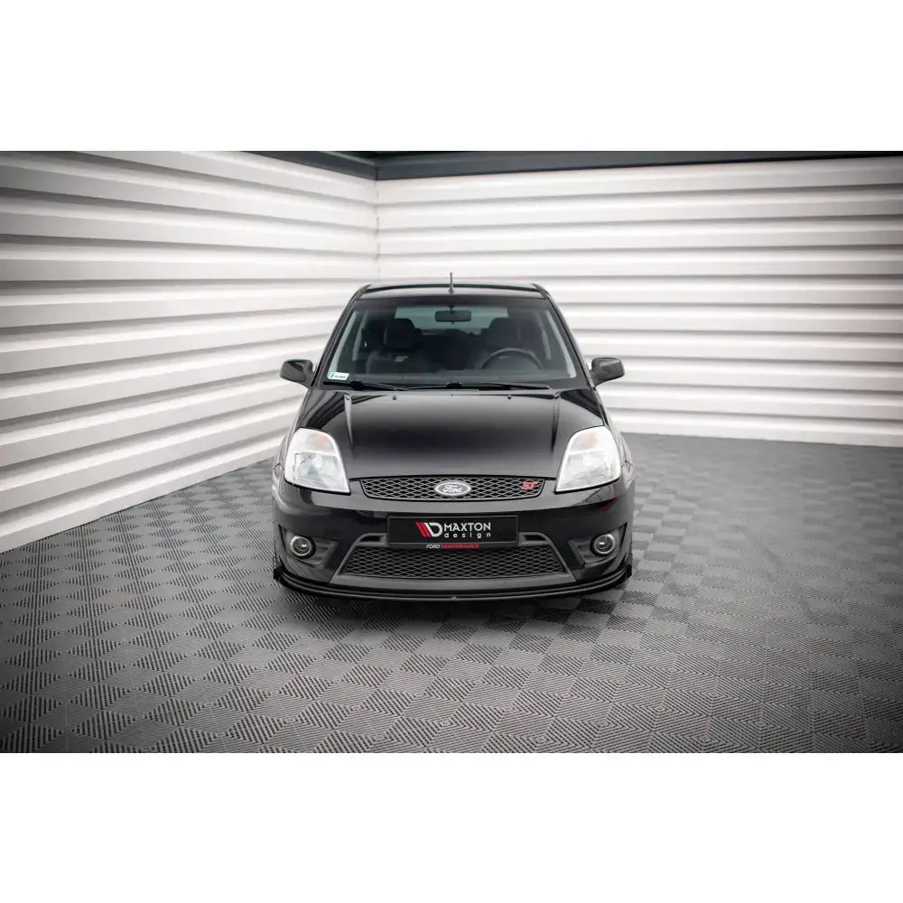 Frontsplitter Street Pro V1 med flaps på svart Ford Fiesta ST Mk6, sett forfra med rødt emblem.