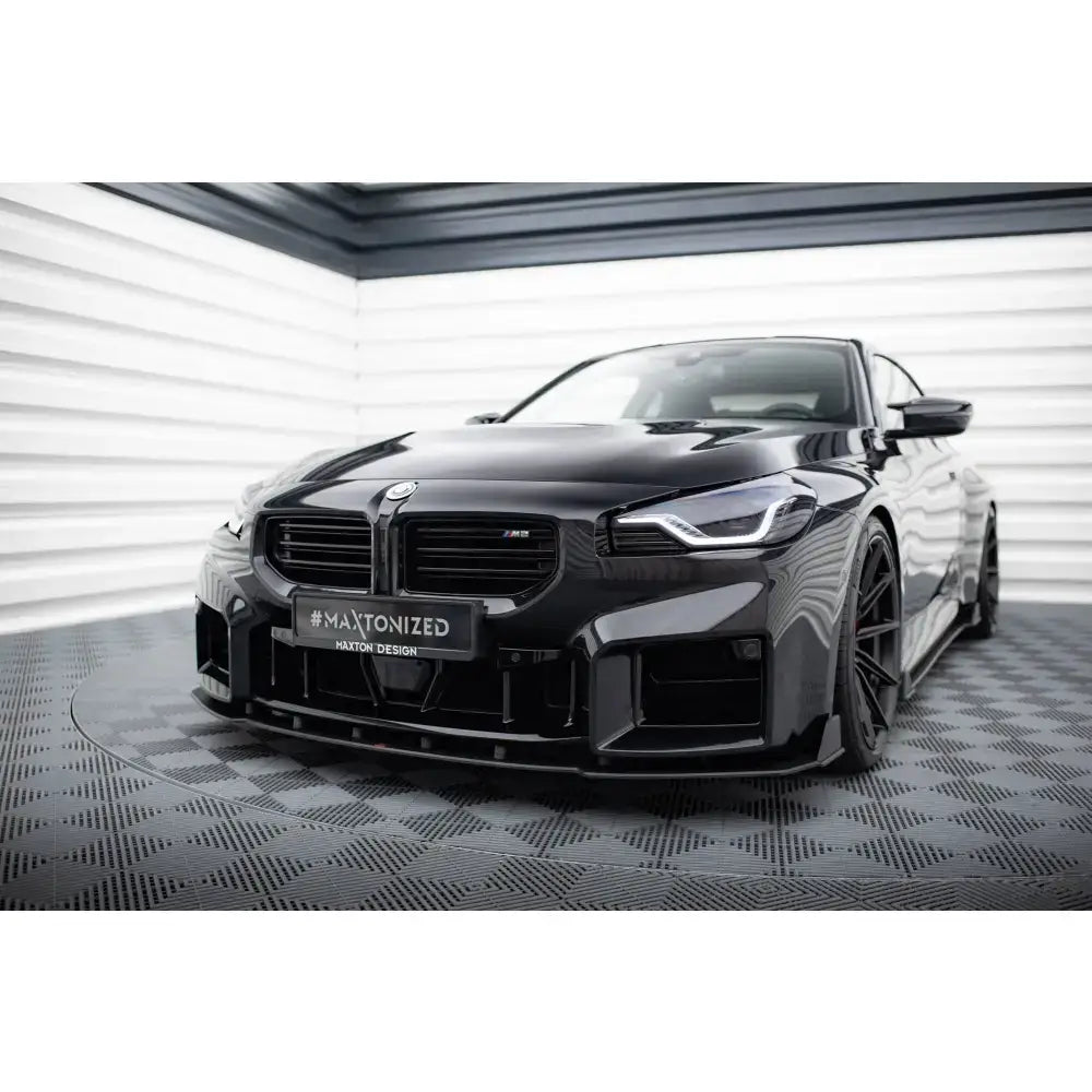 Frontspoiler Street Pro V2 på BMW M2 G87, svart bil forfra med lav frontfanger i lyst rom.
