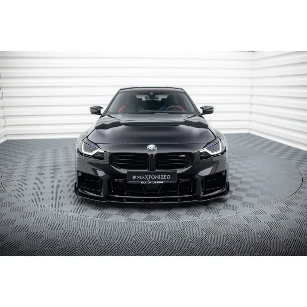 Frontsplitter på BMW M2 G87 Street Pro V2 sett forfra i lyst rom med grått, mønstret gulv.