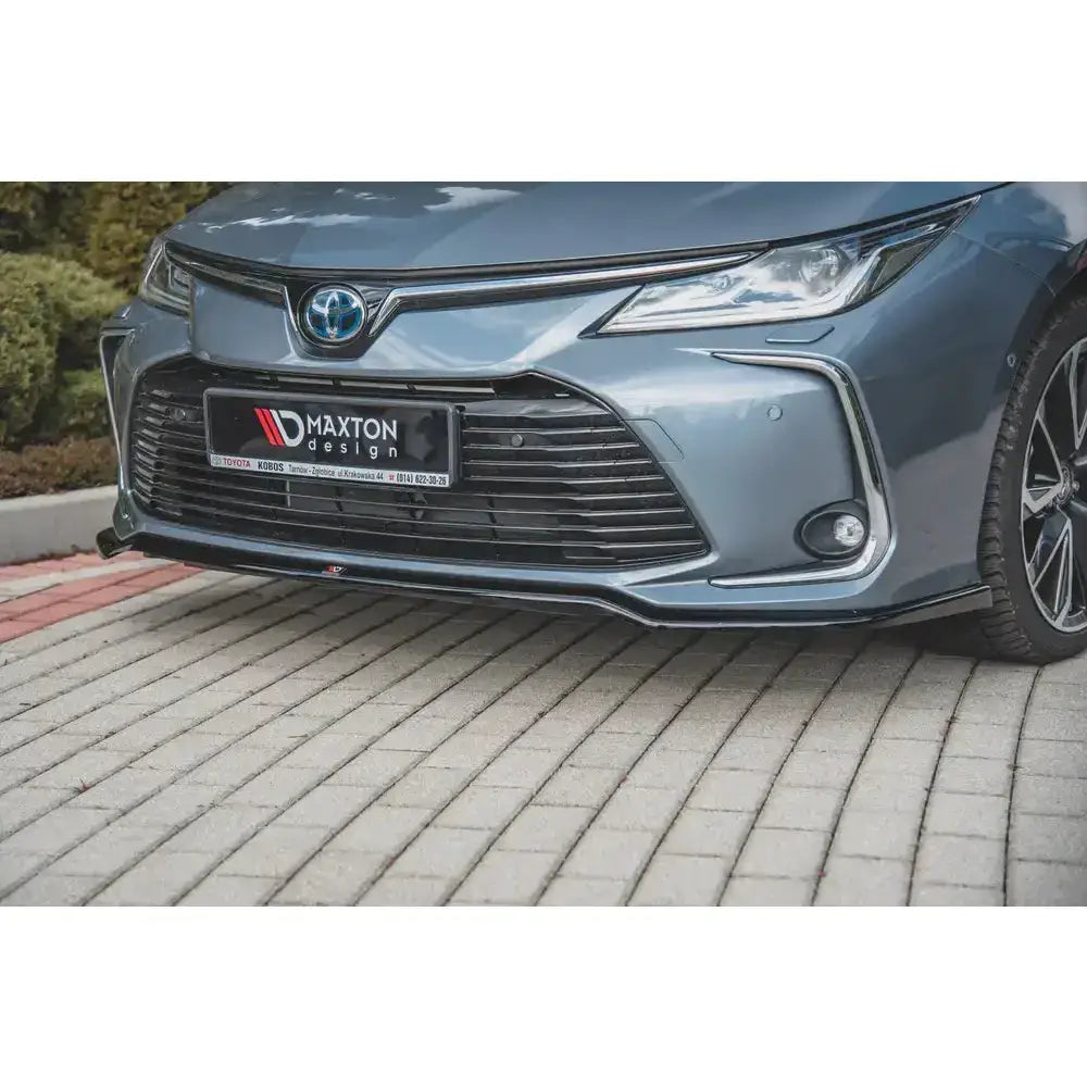Frontsplitter til Toyota Corolla XII Sedan med sporty svart spoiler, nærbilde fra skrå vinkel på grå bil.