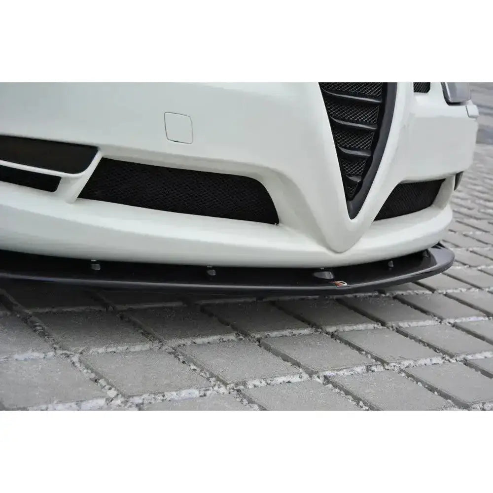Front splitter for Alfa Romeo GT V.1 montert under hvit støtfanger, sett fra lav vinkel på brostein.
