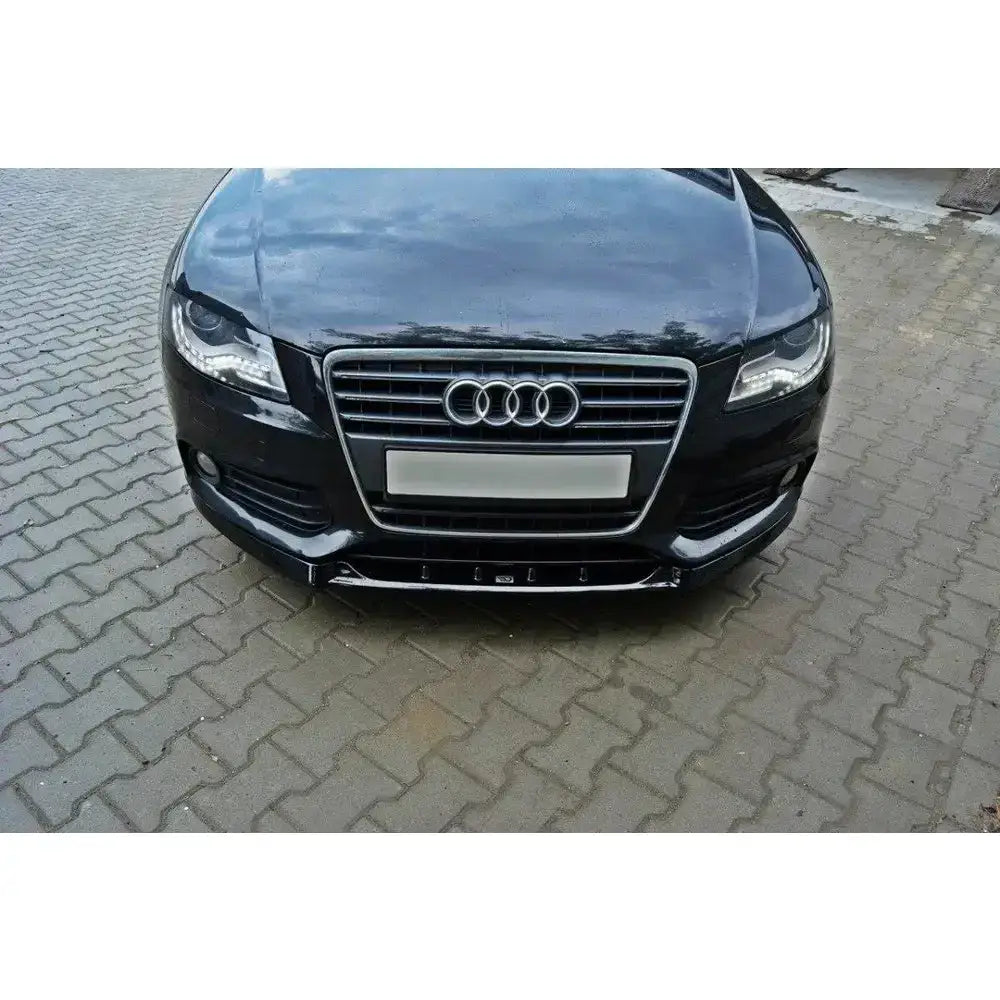Frontsplitter på Audi A4 B8, svart bil sett forfra med kromdetaljer og Audi-logo på brostein.