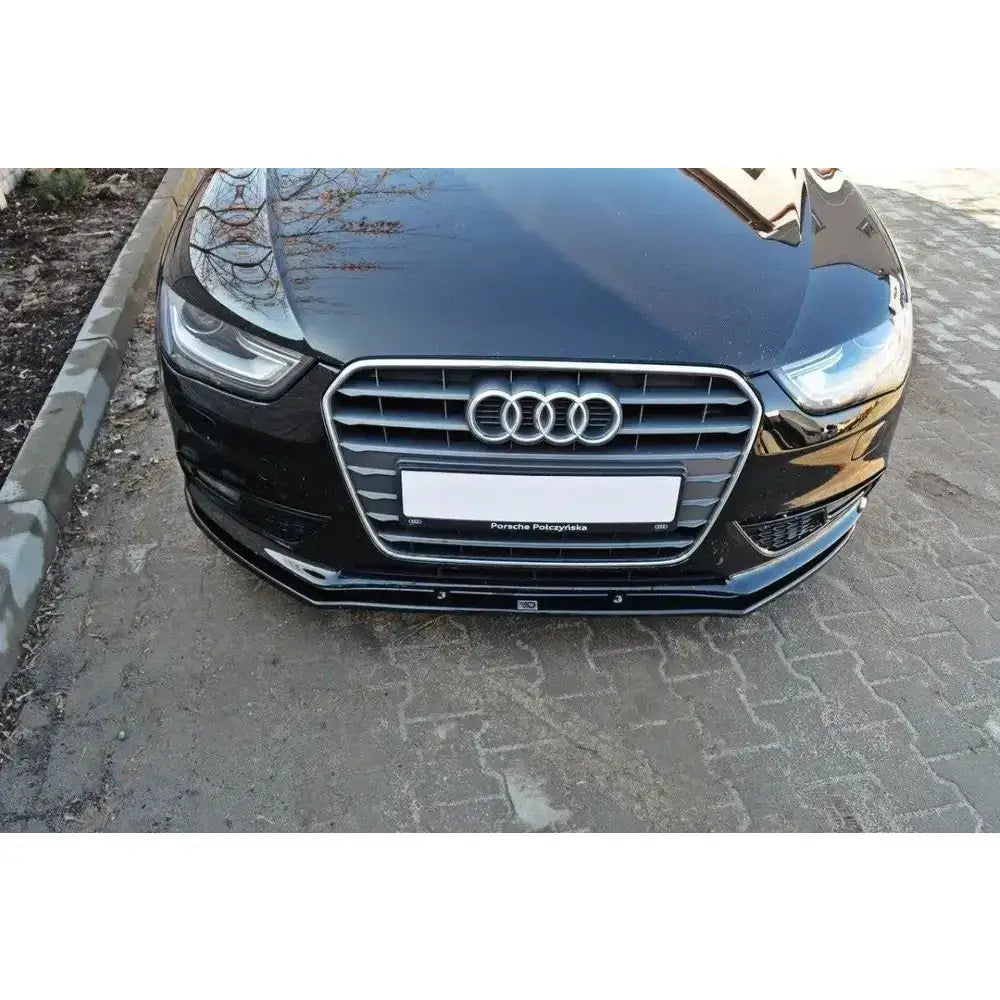Frontspoiler på sort Audi A4 B8 FL med sølv grillramme, sett forfra på brosteinsbelagt vei.