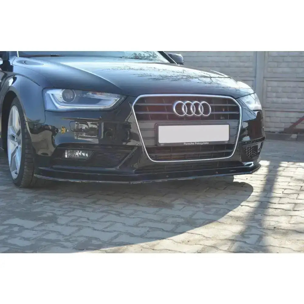 Frontsplitter Audi A4 B8 FL vist på sort bil med grill og logo, fotografert utendørs på brostein.