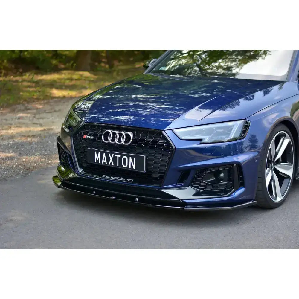 Front lip Audi Rs4 B9 med blank sort finish montert på blå bil, sett forfra i halvprofil.