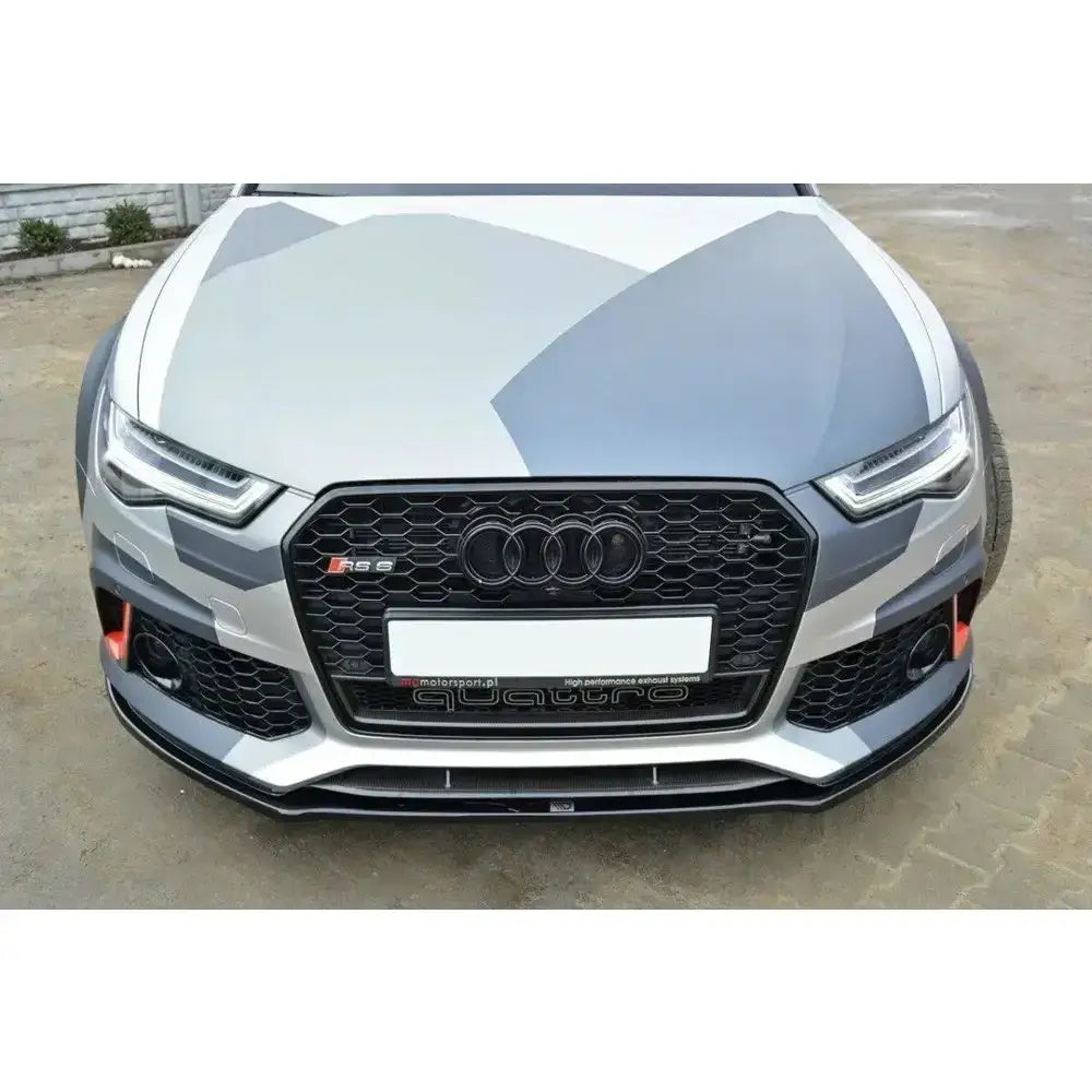Frontsplitter på Audi RS6 C7 med kamuflasjedesign, stor svart grill og quattro-merke utendørs.