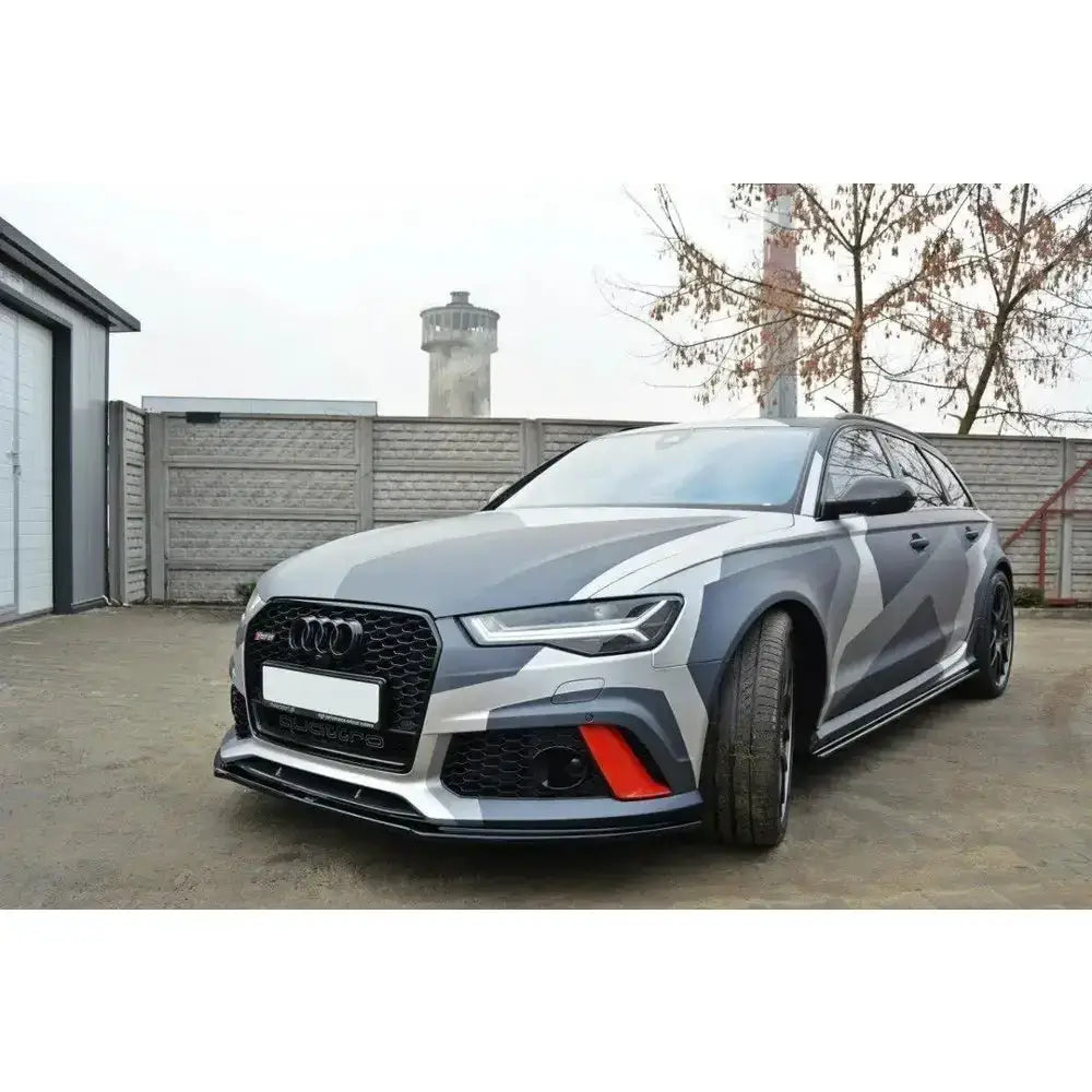 Front splitter på Audi RS6 C7 med grått kamuflasjedesign og sorte felger, sett skrått forfra.
