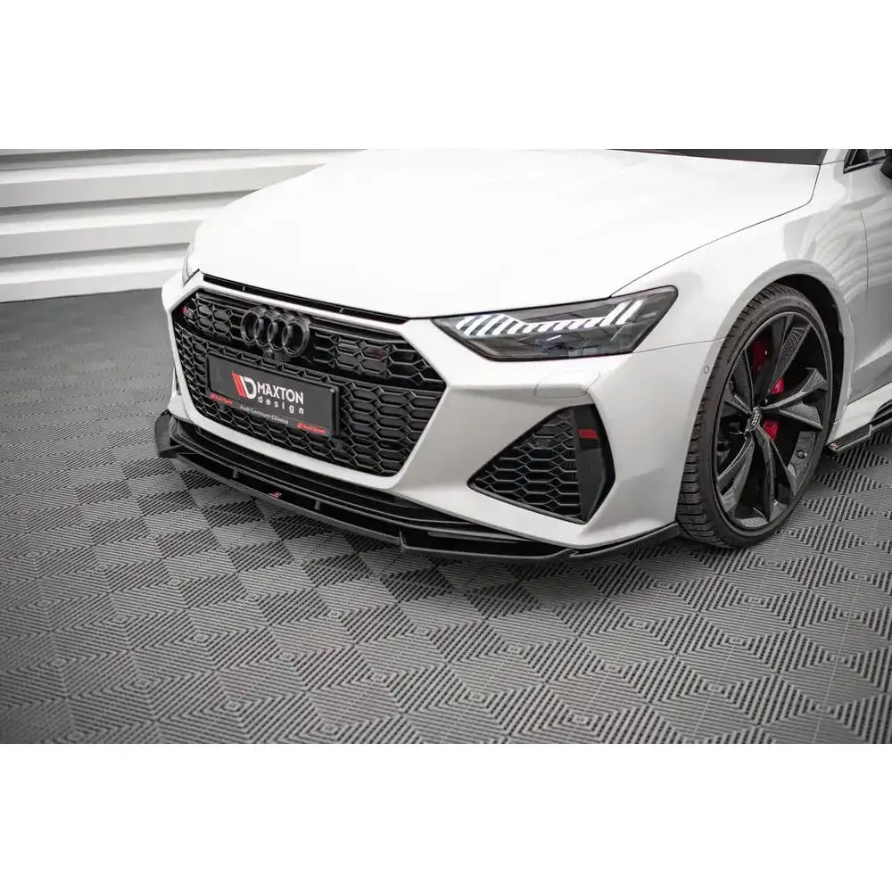 Frontsplitter på Audi RS6 C8 med svart grill, store sorte felger og røde bremsekalipere.