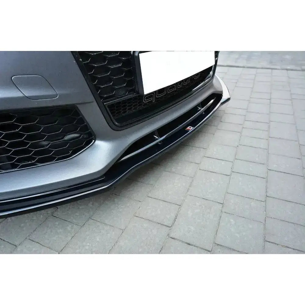 Front lip av Audi RS7 Facelift med svart splitter og synlig S-logo, sett fra siden i nærbilde.