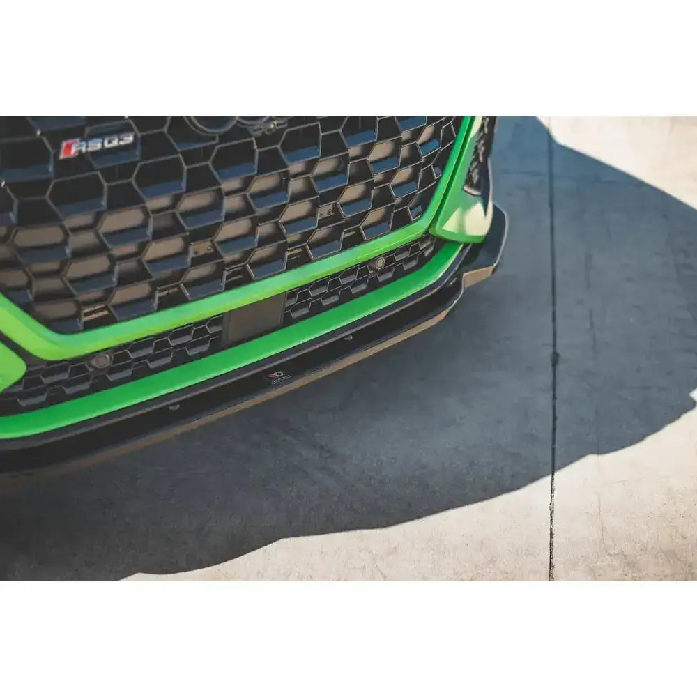 Front splitter på Audi RSQ3 F3 med sort bikakemønstret grill, grønn kant og synlig RS-logo.