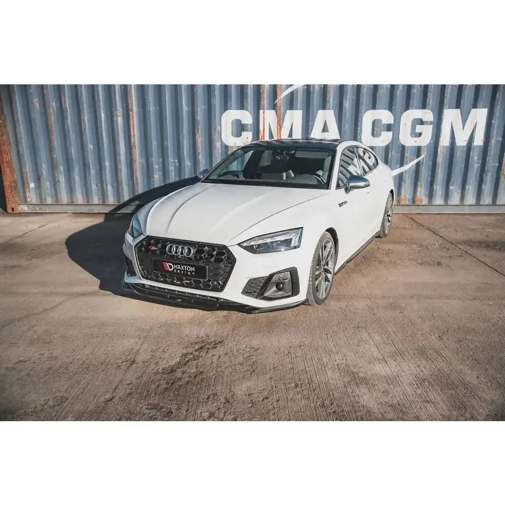 Frontspoiler på Audi S5 F5 Facelift med sorte detaljer, fotografert utendørs foran blå konteiner.
