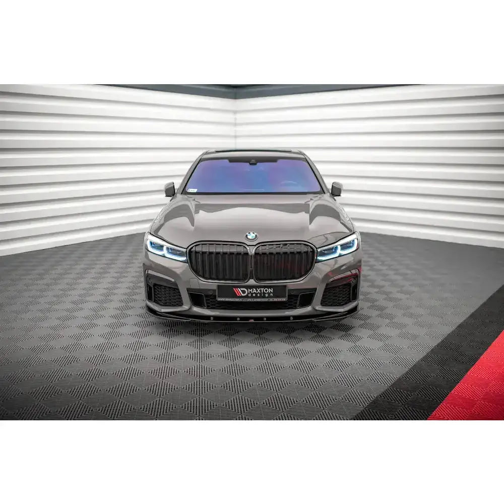 Frontspoiler på grå BMW 7 G11 M-Pack Facelift med sorte detaljer og blå frontlykter, sett forfra.