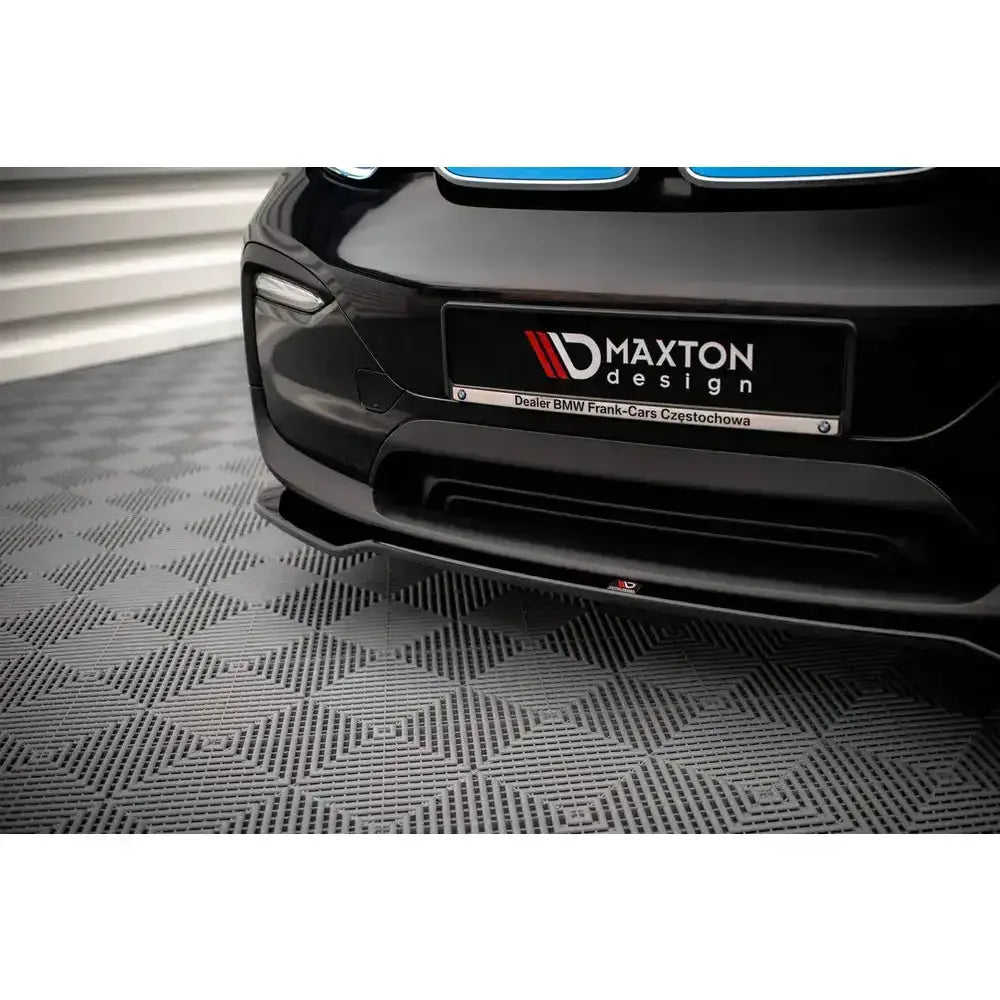Frontspoiler til Bmw i3 Mk1 Facelift vist i sort plast under støtfanger på grått gulv.