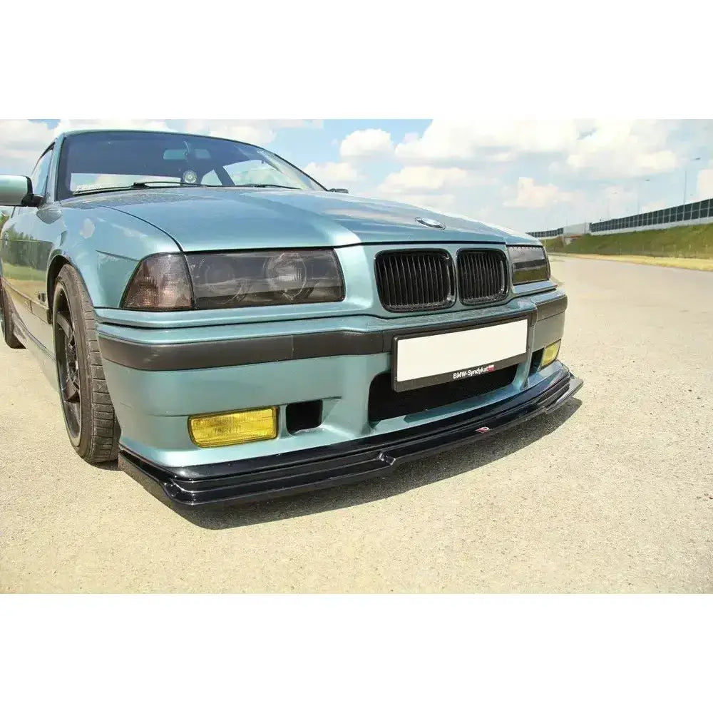 Frontspoiler til Bmw M3 E36 V.1 montert på lyseblå bil med sorte detaljer og gul tåkelykt.