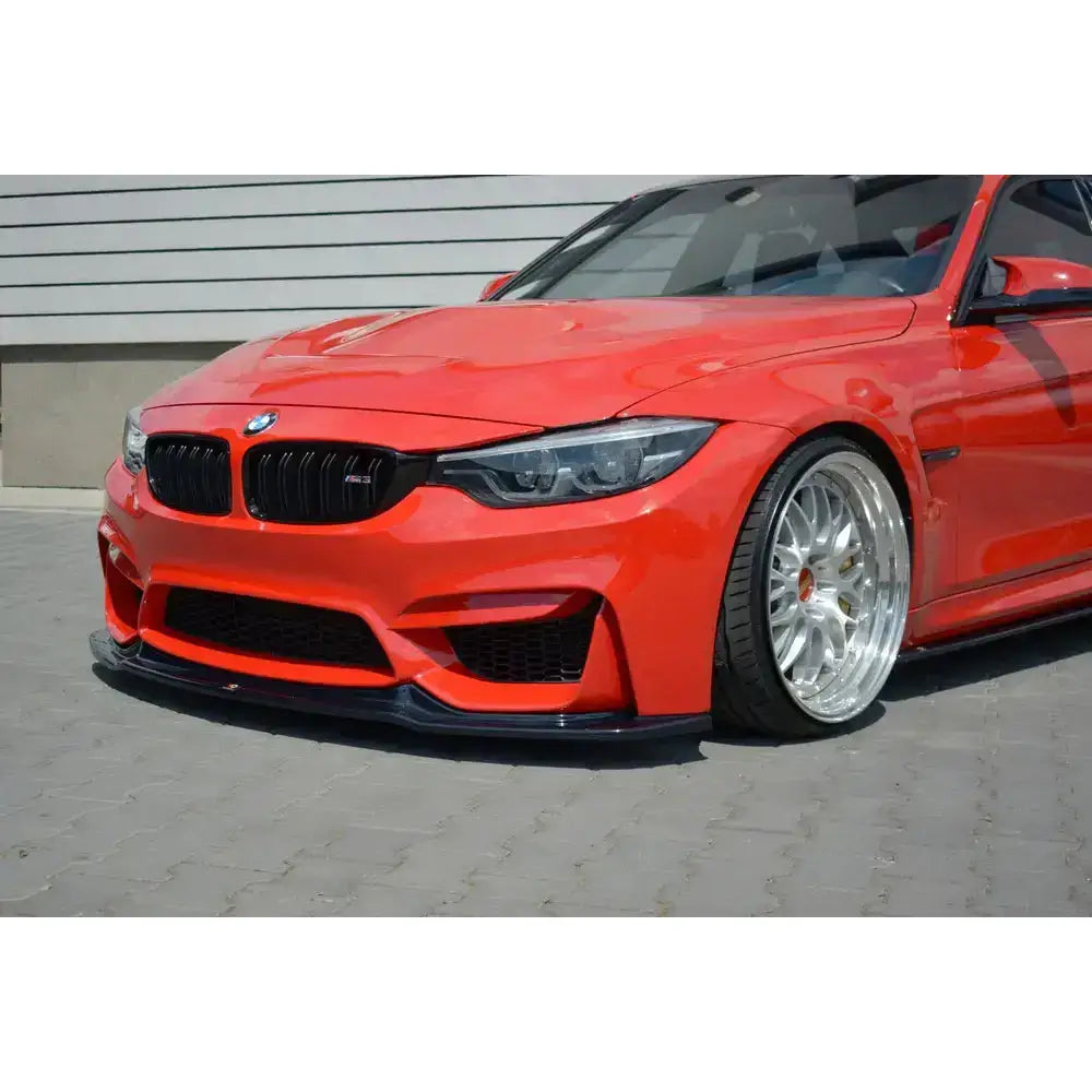 Frontsplitter på rød Bmw M3 F80 med blanke fler-eike felger og lav front sett skrått forfra.