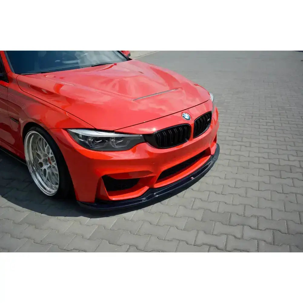 Front lip på Bmw M3 F80 V.1 montert på rød sportsbil med sorte grilldetaljer og sølvfelger.