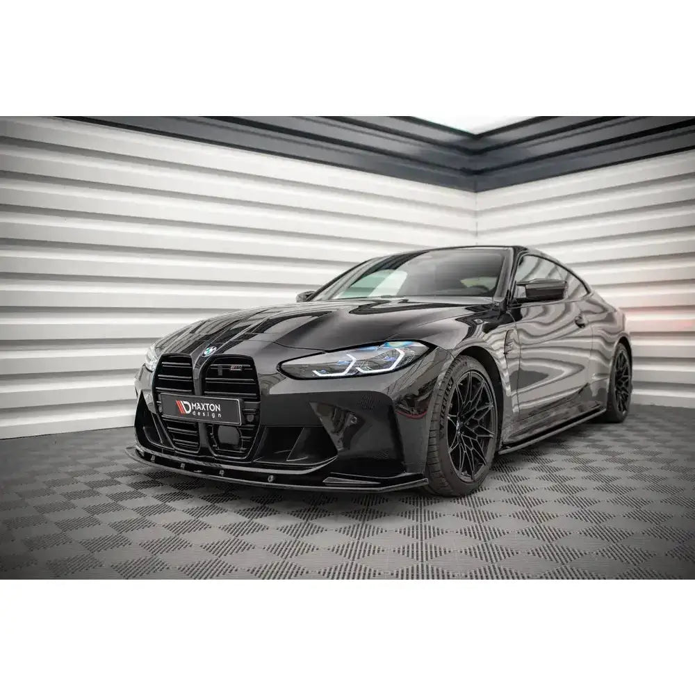 Frontspoiler på BMW M4 G82 V.1, sort sportsbil med svarte felger og store luftinntak, innendørs.