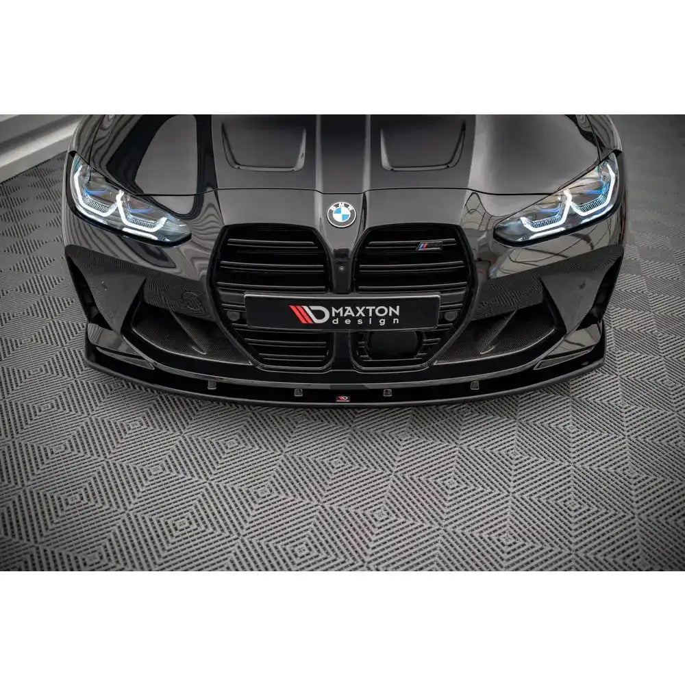 Frontsplitter på BMW M4 G82 V.1, sort glanset finish og karbonfiber, sett rett forfra på grått gulv.