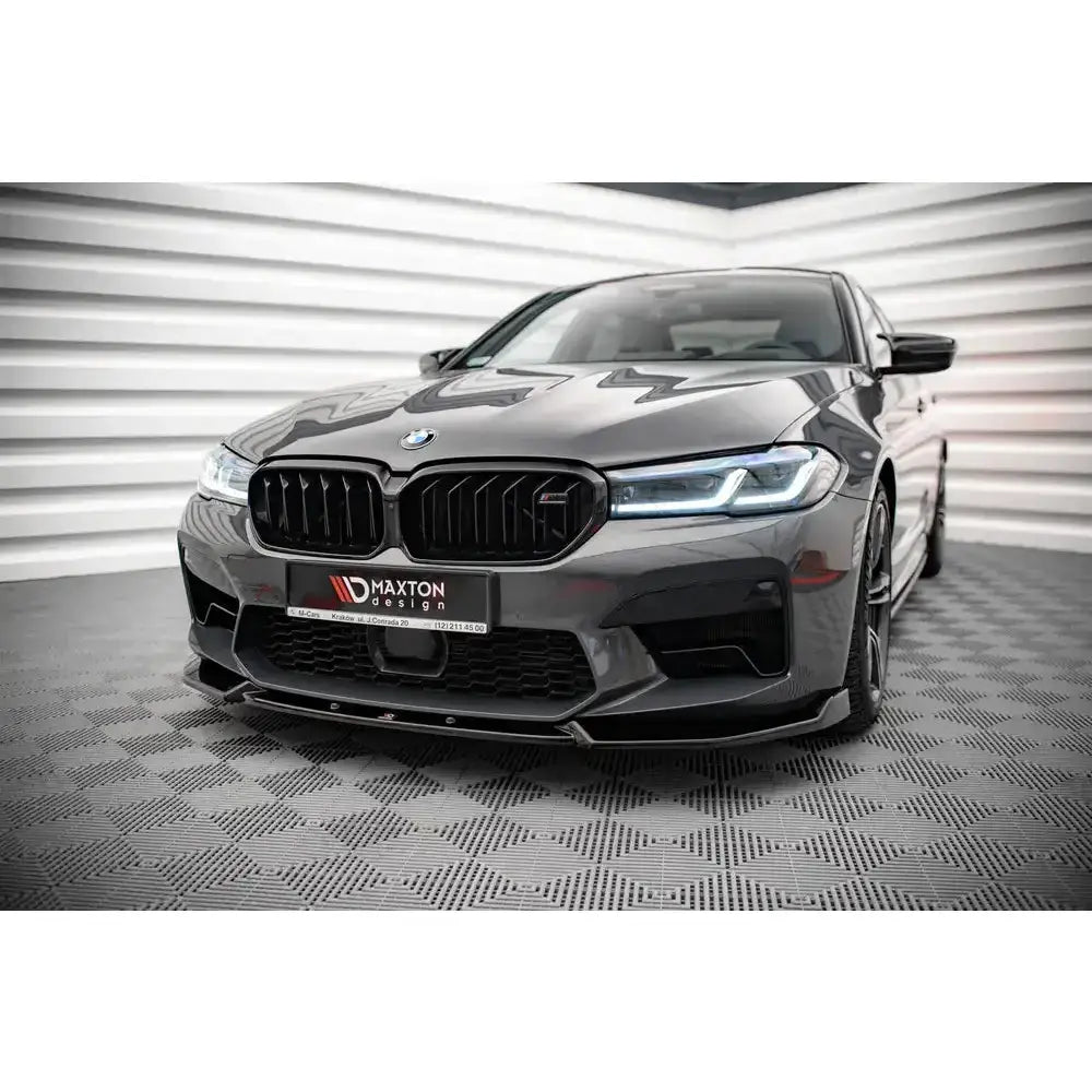 Frontsplitter på BMW M5 F90 Facelift med sorte detaljer og Maxton Design-logo foran i lyst rom.