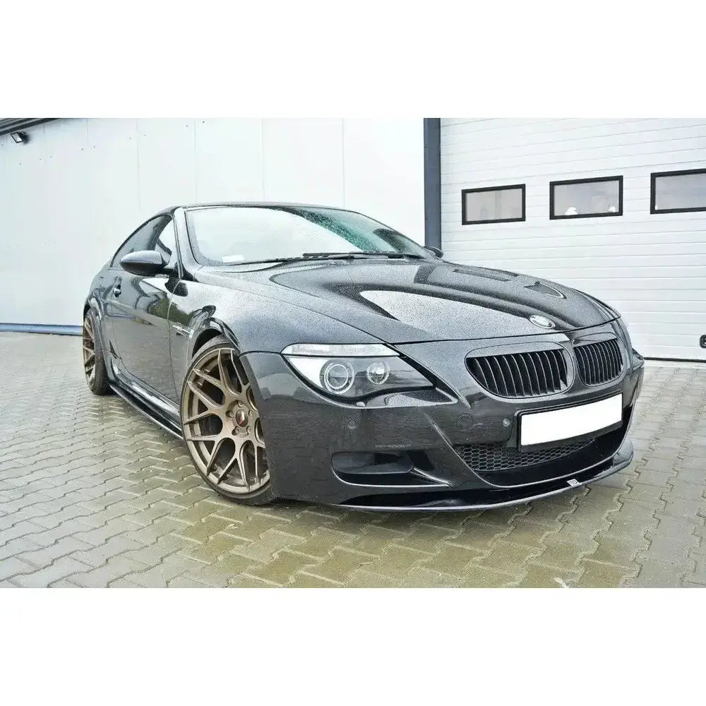 Frontspoiler på Bmw M6 E63 i mørk grå farge med bronsefargede felger og regndråper på panseret.