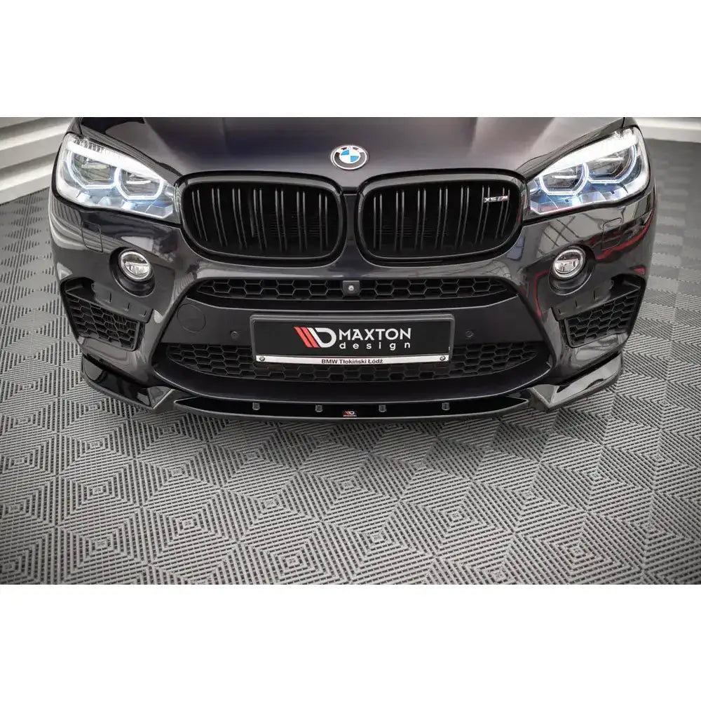 Frontsplitter på Bmw X5 M F15 14-18, sett forfra med sorte detaljer og tent LED-lys på geometrisk bakgrunn.