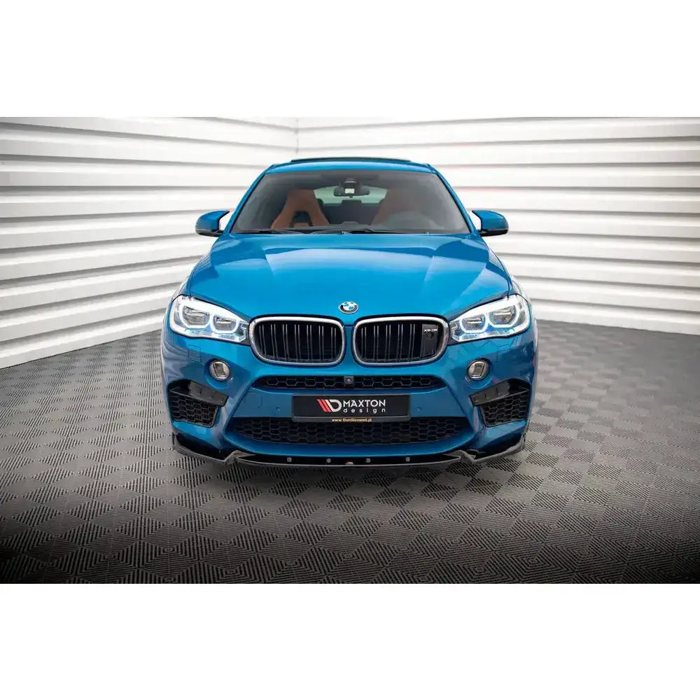 Front splitter på blå BMW X5 M F15 med svarte grilldetaljer og LED-lys, fotografert forfra innendørs.
